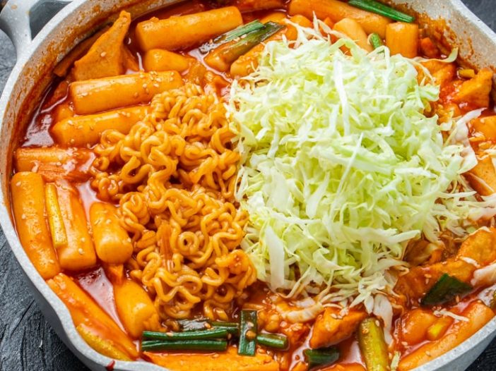 large saute pan with rabokki, topped with shredded cabbage
