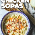 Vegan chicken sopas (macaroni soup) in a blue rimmed bowl with wooden ladle and an onion around it