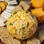 Vegan Cheddar Cheese Ball on a cheese board surrounded by vegan cheese & crackers