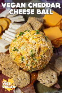Vegan Cheddar Cheese Ball on a cheese board surrounded by vegan cheese & crackers
