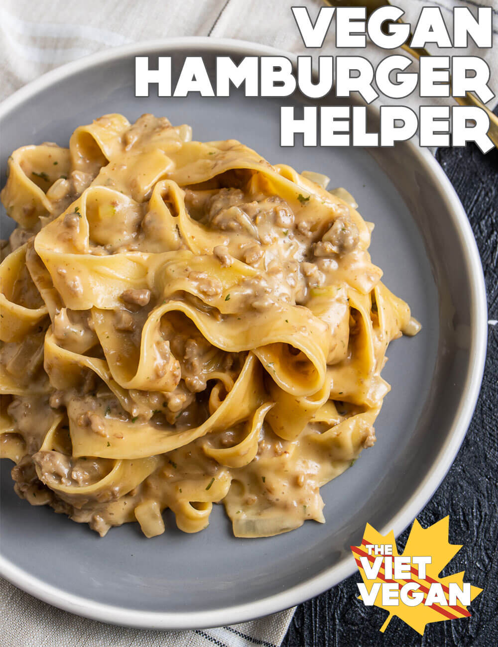 a serving of the finished pasta with parpadelle on a grey plate, on top of a beige plaid tea towel