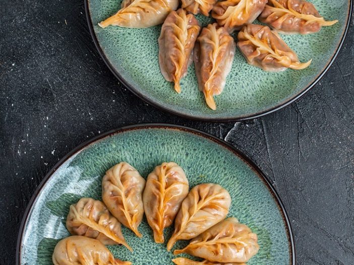two plates of red curry braided dumplings, one is steamed, one is steam fried