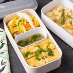 fried tofu with sauce in a bento box with green mango salad, fried rice on the side