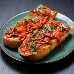 two pieces of toast with garlic tomato confit and text in the corner