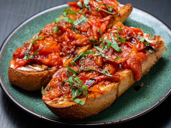 two pieces of toast with garlic tomato confit and text in the corner