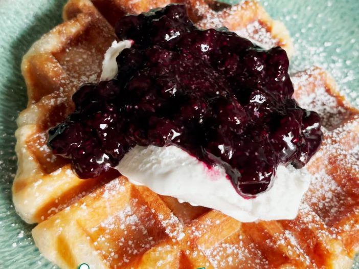 Vegan croissant waffle topped with coconut whip and blueberry chia jam
