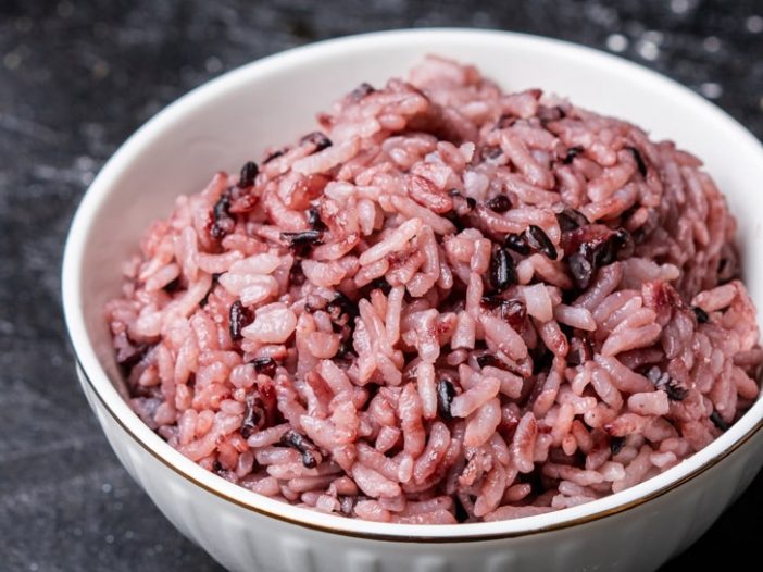 purple rice in a small rice bowl, off center on a dark background