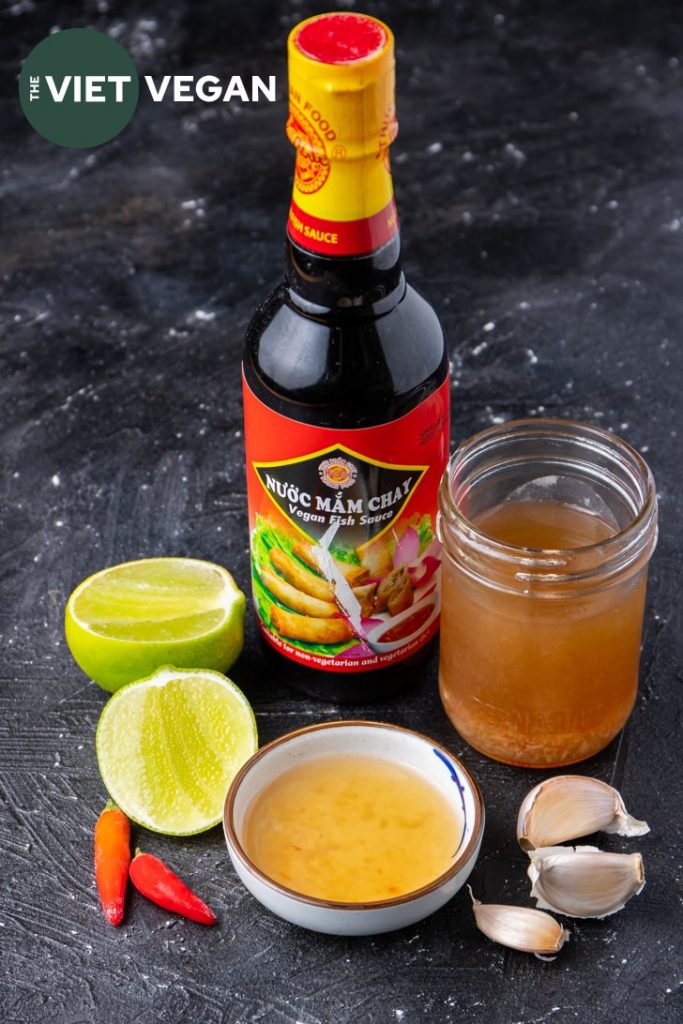 nuoc cham with vegan fish sauce bottle, surrounded by lime, garlic, and chili pepper