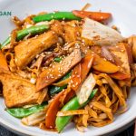 chow mein stir fried with vegetables in a white bowl on a dark background