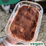 Container of vegan biscoff tiramisu, top layer view of dusted cocoa powder