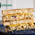 chickpea tuna sandwich cut in half and stacked on a blue plate, closeup
