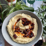 The creamiest hummus in a serving bowl with chili crisp on top