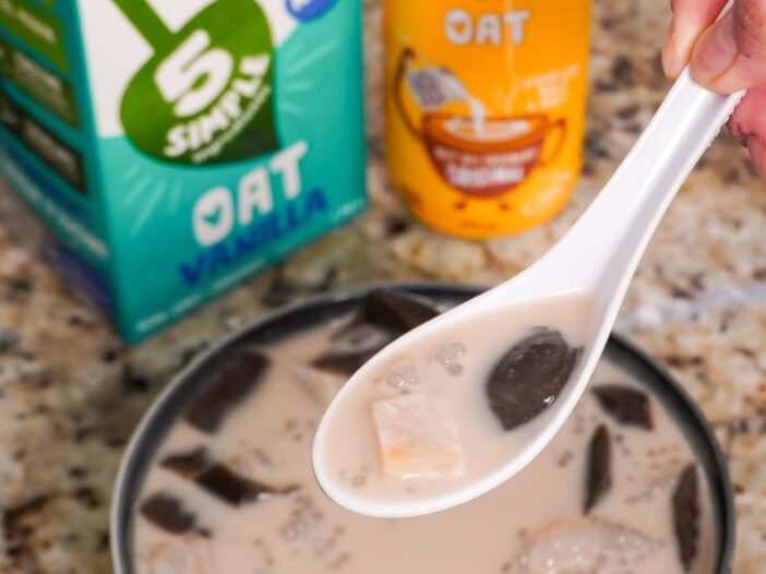 an asian soupspoon filled with taro, sago, grass jelly and sweetened oat milk