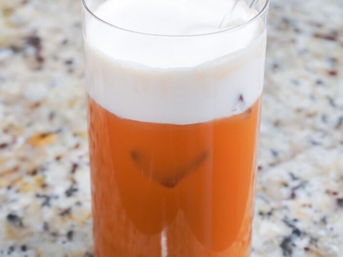 vegan thai iced tea in a glass with a layer of vegan cheese foam on top