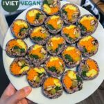 vegan kimbap made with purple rice arranged on a white plate