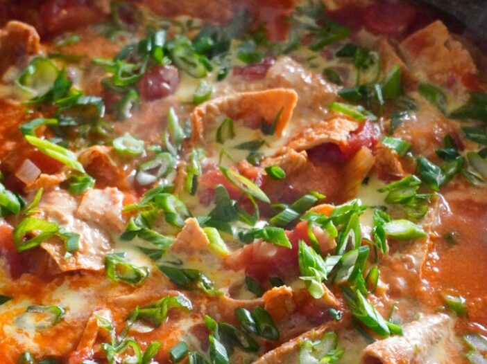 vegan tomato egg in a large wok made with fried bean curd and topped with scallions