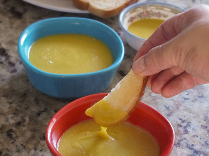 a toast stick dipped into the vegan egg yolk sauce