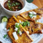 vegan birria tacos with soy curls plated with onion and cilantro with consomme