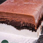 cross section of ice cream cake with chocolate ice cream, ganache, cookie crumble, and vanilla ice cream layers