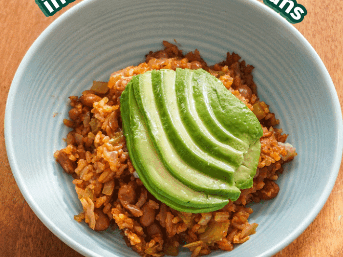 tomato rice and beans in a blue bowl with avocado fanned on top