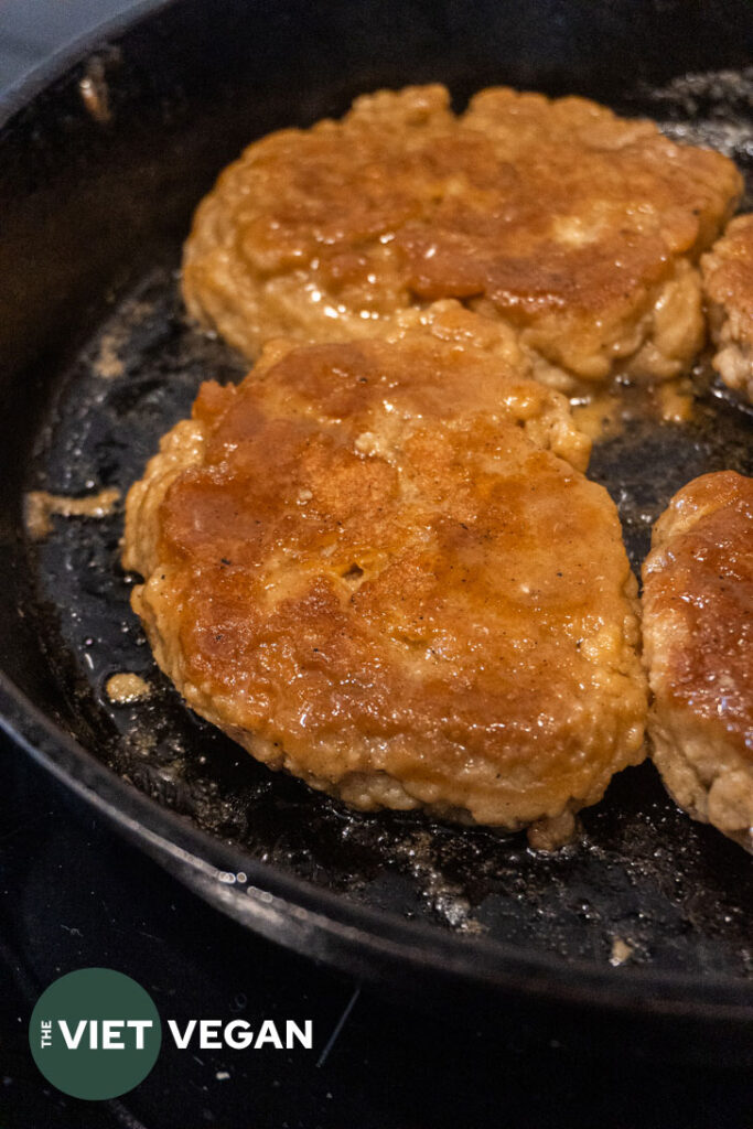 Seitan steaks cooking in a cast iron skillet