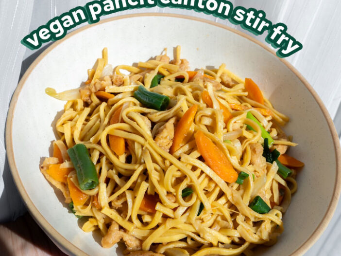 vegan stir fry in a white bowl in front of a white sheer curtain