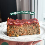 a slice of vegan meatloaf on a plate with a spicy ketchup glaze on top with the words "vegan meatloaf" overhead