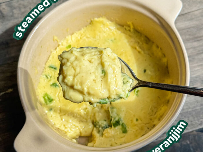 a scoop of the steamed vegan egg in a spoon over a casserole dish of the rest of the steamed egg